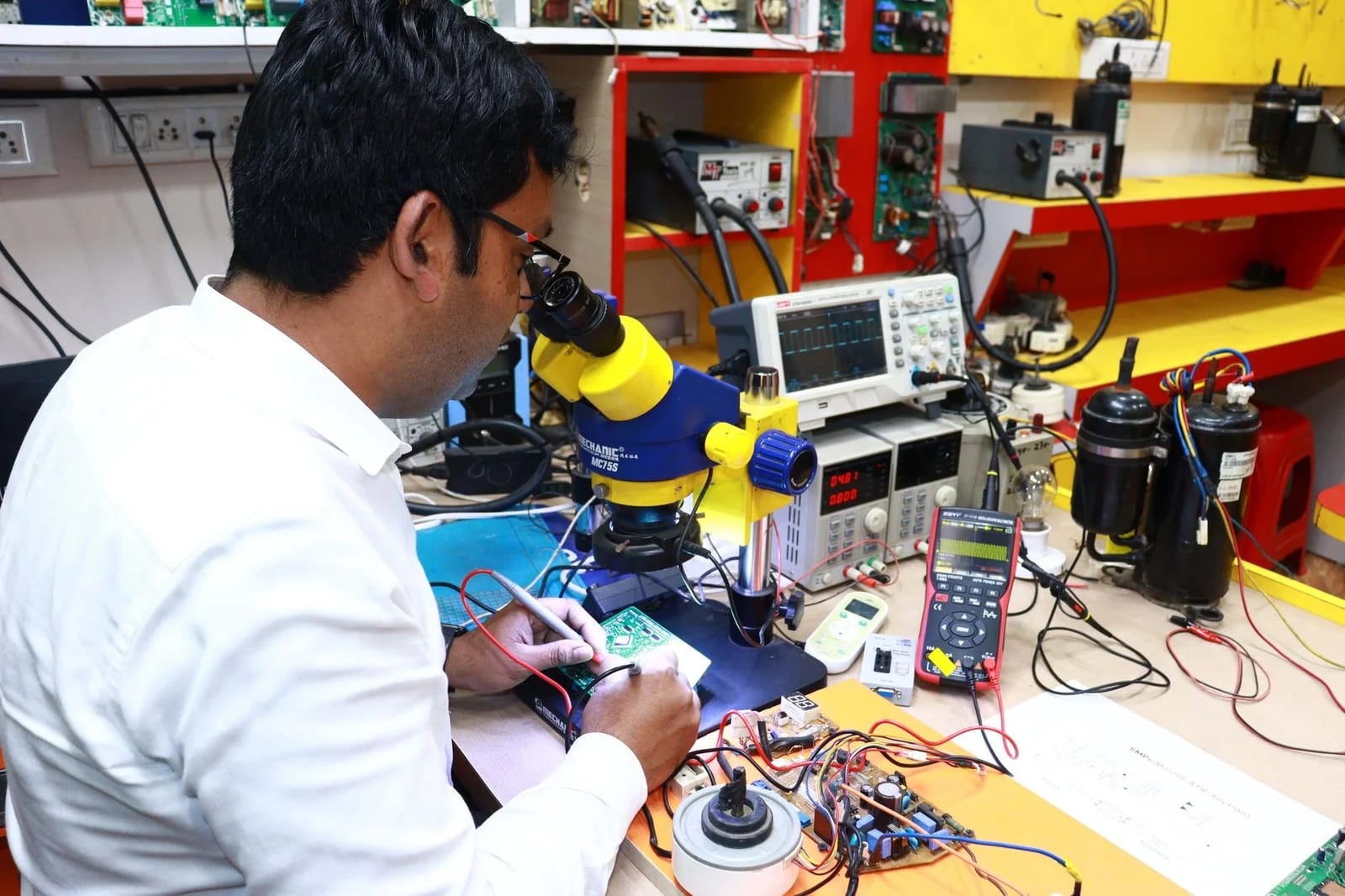 A technician skillfully repairs a PCB using a microscope in a modern electronics lab.